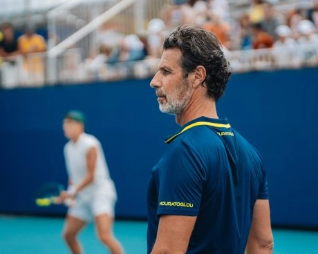 Patrick mouratoglou observing a player during a match on a blue court.