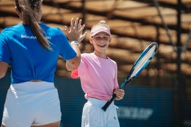 coach mouratoglou tape dans les mains d'une jeune fille en stage