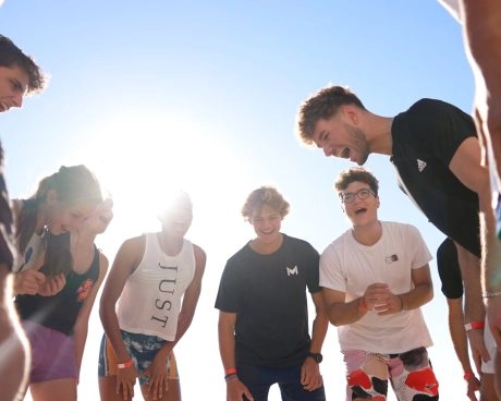 Group of young athletes standing in a circle outdoors during a team activity