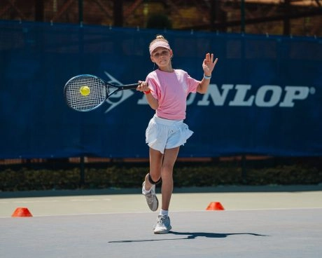 Young girl hitting a forehand during a tennis training session on an outdoor court