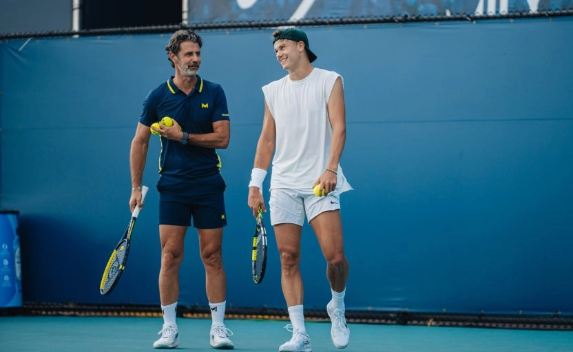 Holger Rune receiving coaching from Patrick Mouratoglou on a tennis court.