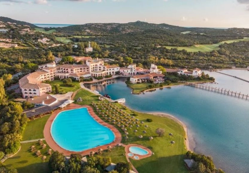 Aerial view of a luxury seaside resort with swimming pools, villas, and a private lagoon