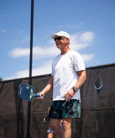 Un joueur pratique le pickleball sur un terrain extérieur au Mouratoglou Tennis Center à Horseshoe Bay par une journée ensoleillée.