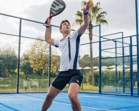 Male padel player preparing an overhead smash on an outdoor blue court