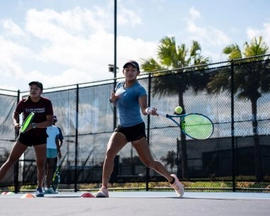 Two female tennis players practicing a forehand drill on an outdoor court