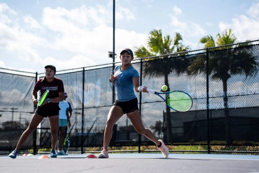 Two female tennis players practicing a forehand drill on an outdoor court