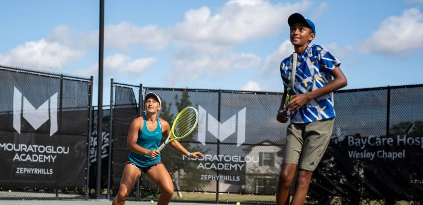 Teen and adult tennis players training together on an outdoor court