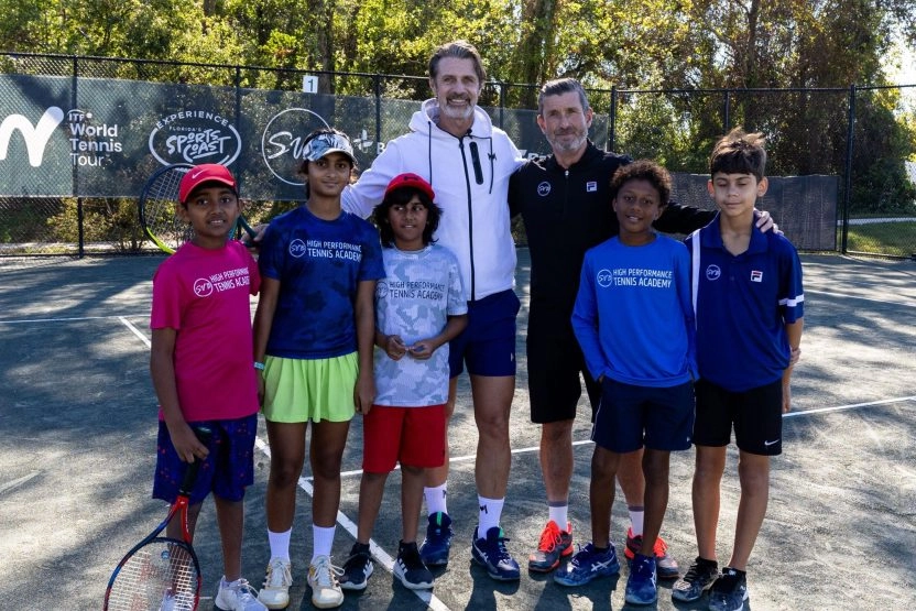 Patrick Mouratoglou standing with a group of young tennis players on an outdoor court at Mouratoglou Academy Zephyrhills.