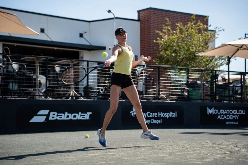 Female tennis player hitting a forehand during training on an outdoor court