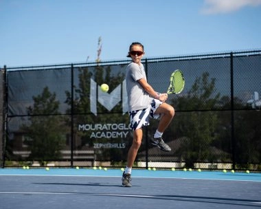 Young tennis player jumping to hit a forehand during training at Mouratoglou Academy