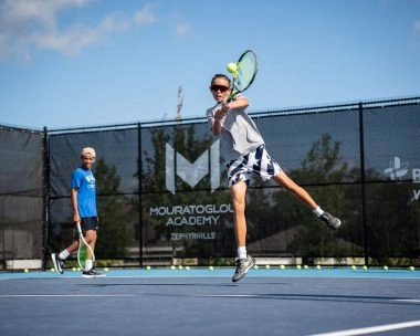 Young tennis player jumping to hit a forehand during training at Mouratoglou Academy