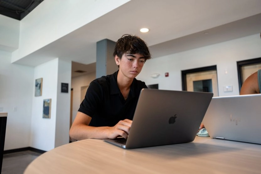 Teen student working on a laptop in a modern study area