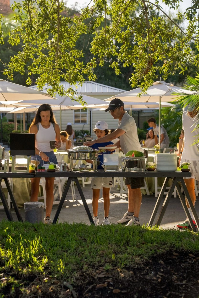 People enjoying an outdoor buffet dining experience at Mouratoglou Tennis Center Naples at The Ritz-Carlton Naples, Tiburón.