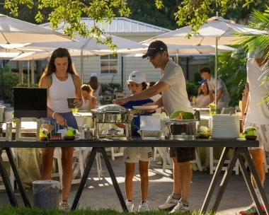 People enjoying an outdoor buffet dining experience at Mouratoglou Tennis Center Naples at The Ritz-Carlton Naples, Tiburón.