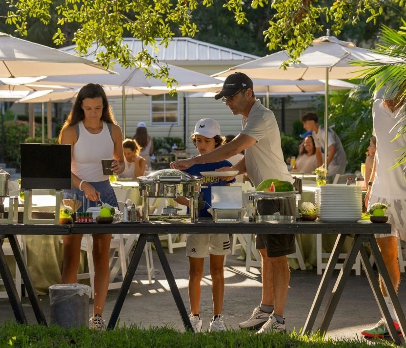 People enjoying an outdoor buffet dining experience at Mouratoglou Tennis Center Naples at The Ritz-Carlton Naples, Tiburón.