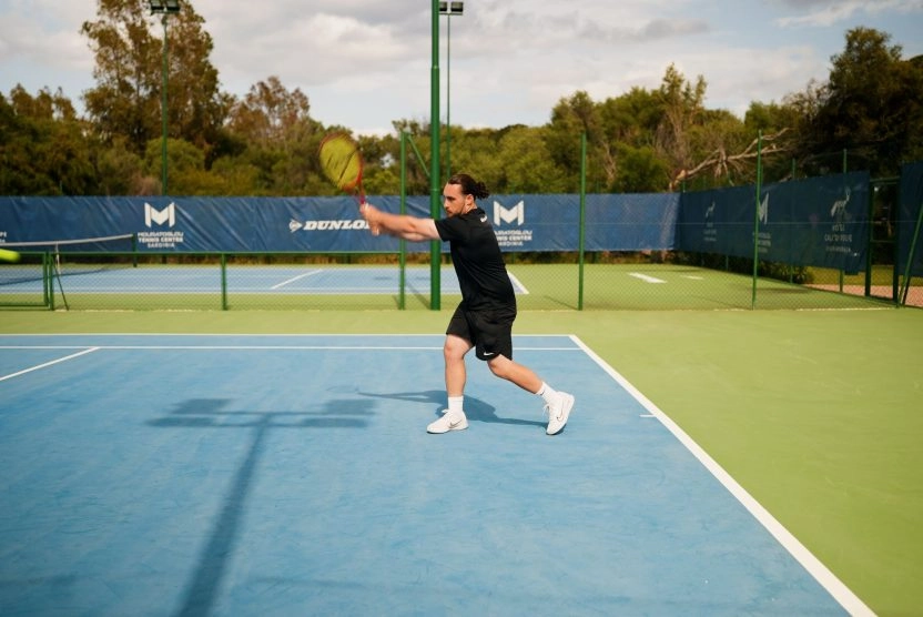Player hitting a forehand on an outdoor court at the Mouratoglou Tennis Center