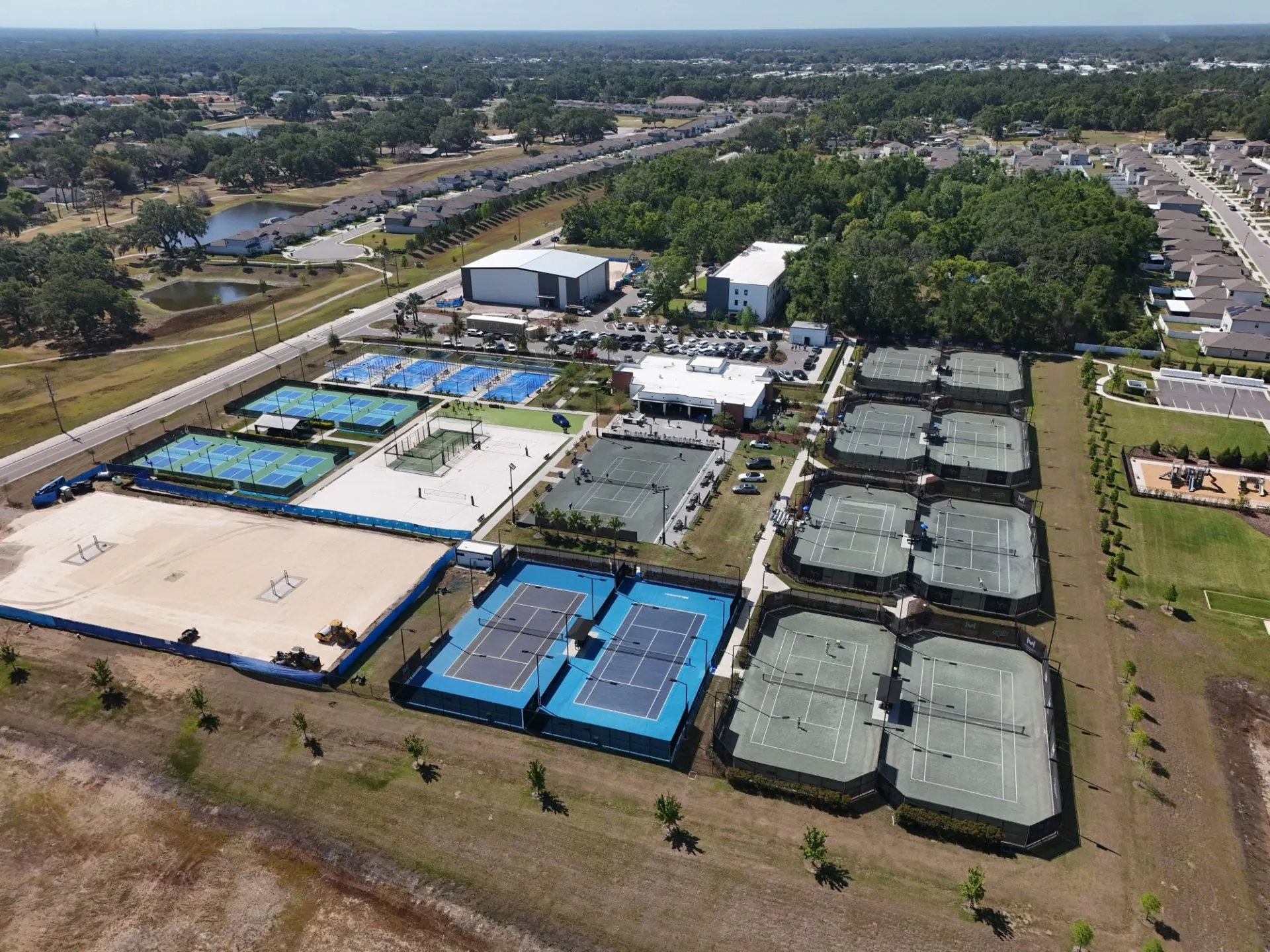 Aerial view of a large sports complex with multiple tennis and pickleball courts