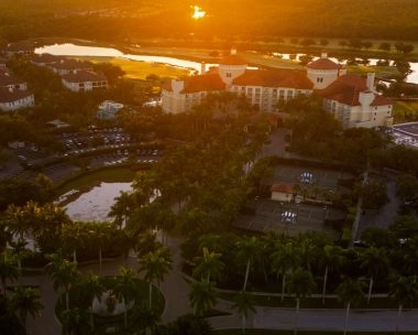 Aerial view of a resort complex at sunset surrounded by lush greenery