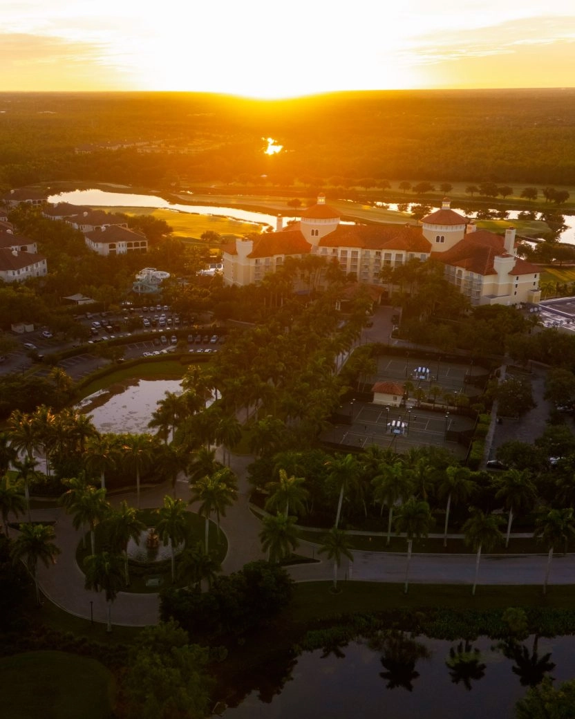 Aerial view of a resort complex at sunset surrounded by lush greenery