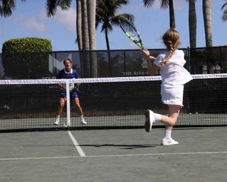 Young girl hitting a tennis shot during a lesson on an outdoor court