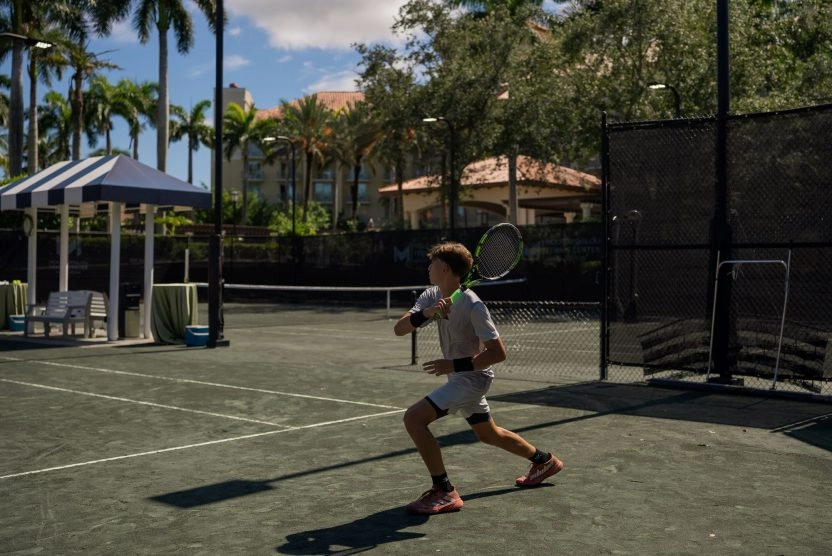 Young tennis player moving to hit a shot on a clay court at Mouratoglou Tennis Center Naples at The Ritz-Carlton Naples, Tiburón.