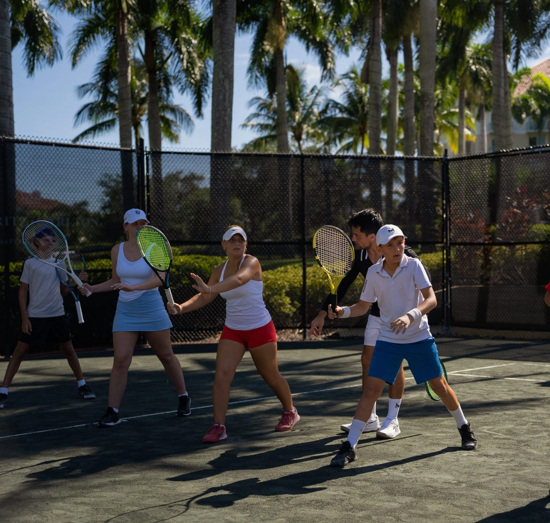Adult tennis players following their coach’s instructions at Mouratoglou Tennis Center Naples, Florida