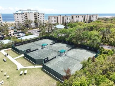 Three Mouratoglou Tennis Center courts surrounded by palm trees and sunshine