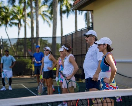 Adult tennis players attending a coaching session on an outdoor court