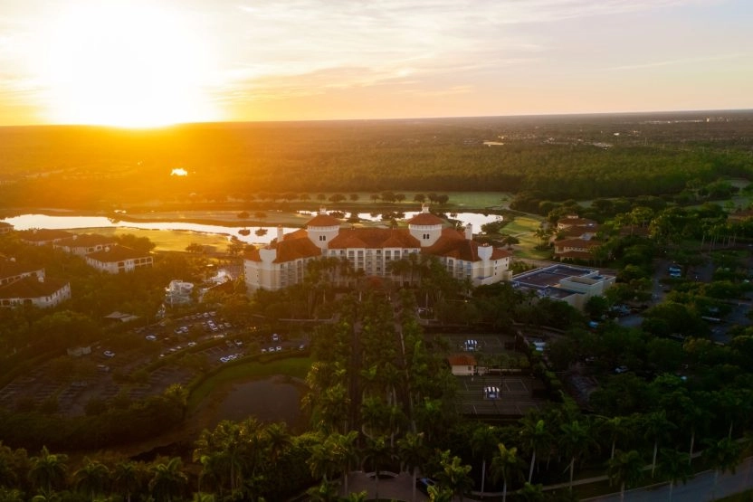 Aerial view of a resort complex at sunset surrounded by lush greenery