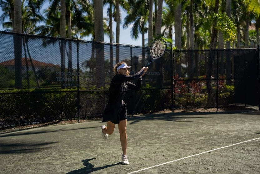 Woman hitting a forehand during training on an outdoor clay tennis court