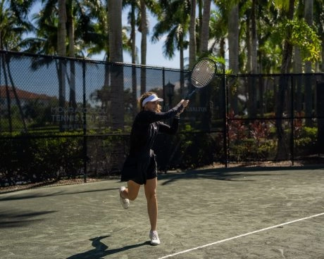 Woman hitting a forehand during training on an outdoor clay tennis court