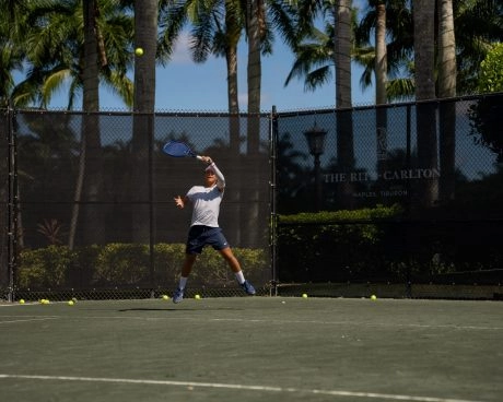 Tennis player hitting a forehand on an outdoor court at The Ritz-Carlton