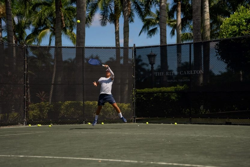 Tennis player hitting a forehand on an outdoor court at The Ritz-Carlton