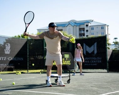 Coach feeding tennis balls on the courts of Mouratoglou Tennis Center Amelia IslandA Mouratoglou coach feeds tennis balls during a training session on the courts of the Mouratoglou Tennis Center Amelia Island. This image captures the precision, rhythm, and expertise of Mouratoglou coaching — creating the perfect conditions for focused and effective practice