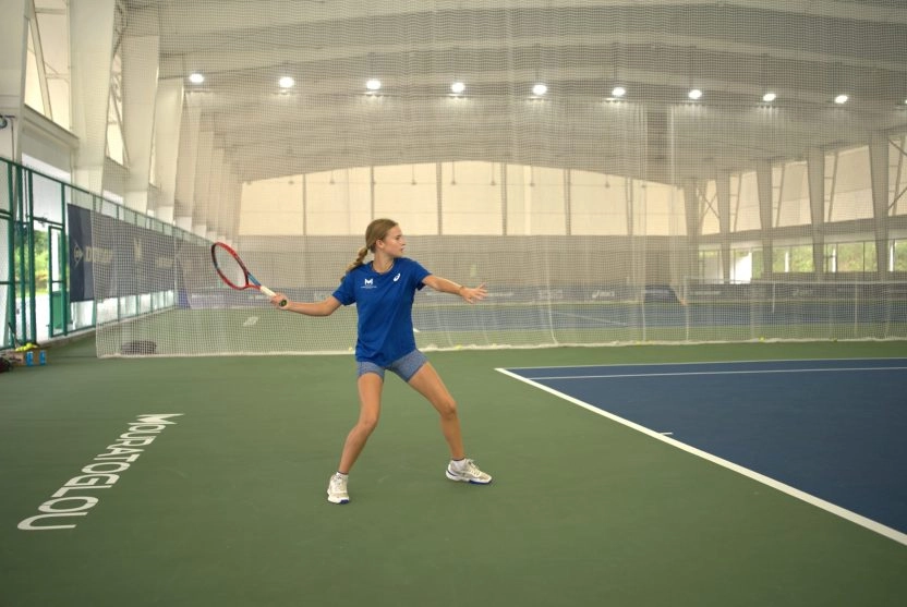 Young tennis player preparing a forehand on an indoor court at the Mouratoglou Academy