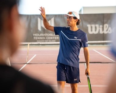 Tennis coach giving on-court instructions at Mouratoglou Tennis Center Hudayriyat Island in Abu Dhabi, guiding players with focus and expertise.