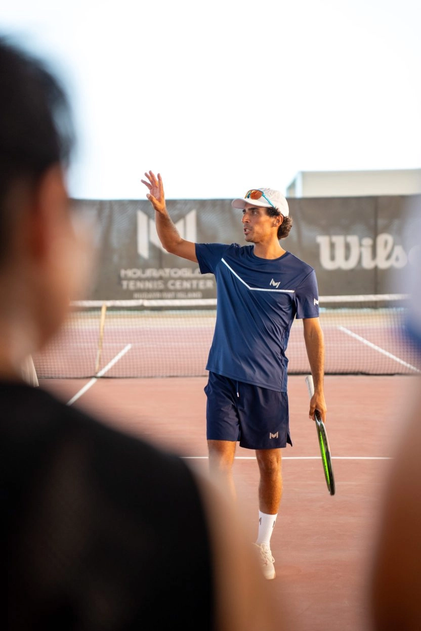 Tennis coach giving on-court instructions at Mouratoglou Tennis Center Hudayriyat Island in Abu Dhabi, guiding players with focus and expertise.