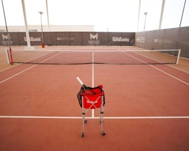 Wilson tennis ball bag placed on the court at Mouratoglou Tennis Center Hudayriyat Island in Abu Dhabi, symbolizing professional training and performance.