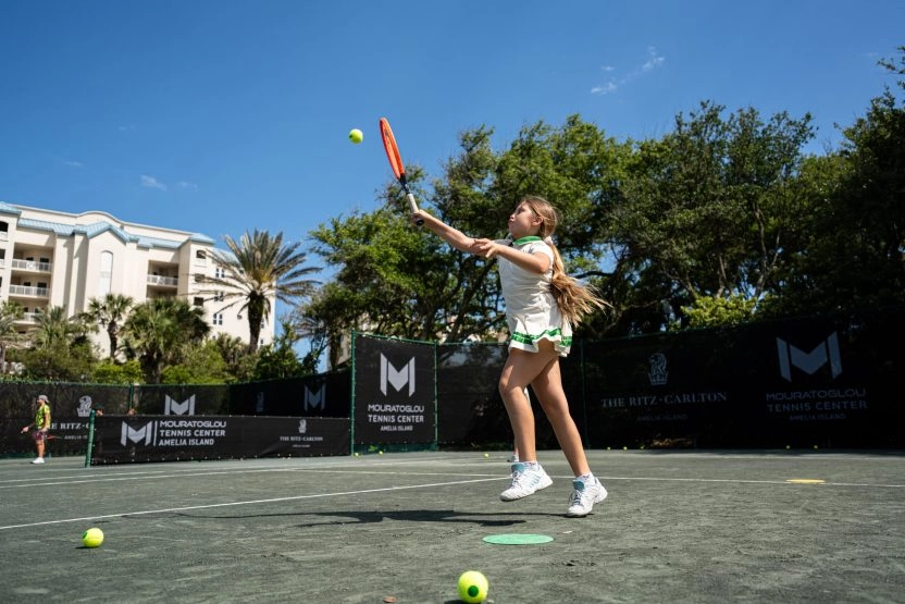 Young girl receiving a tennis ball at the Mouratoglou Tennis Center.