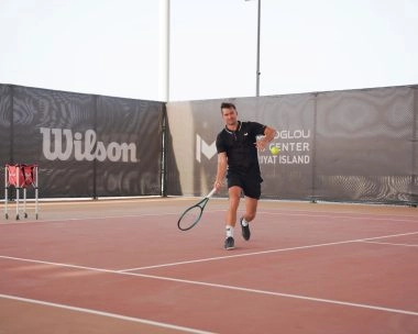 Tennis player receiving a ball on the courts of Mouratoglou Tennis Center Hudayriyat Island in Abu Dhabi, focusing on timing and control.