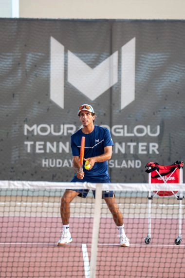 Coach Jaime at Mouratoglou Tennis Center Hudayriyat Island in Abu Dhabi, preparing to return a ball during a tennis session.