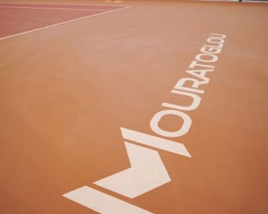 Mouratoglou logo stencil on the tennis court surface at Mouratoglou Tennis Center Hudayriyat Island in Abu Dhabi.