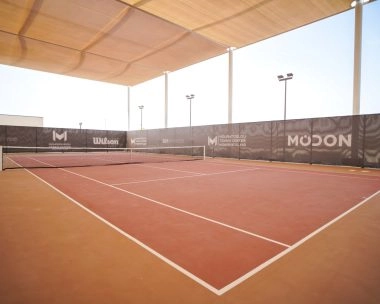 Tennis court at Mouratoglou Tennis Center Hudayriyat Island in Abu Dhabi, featuring high-quality hard surfaces surrounded by palm trees and ocean views.