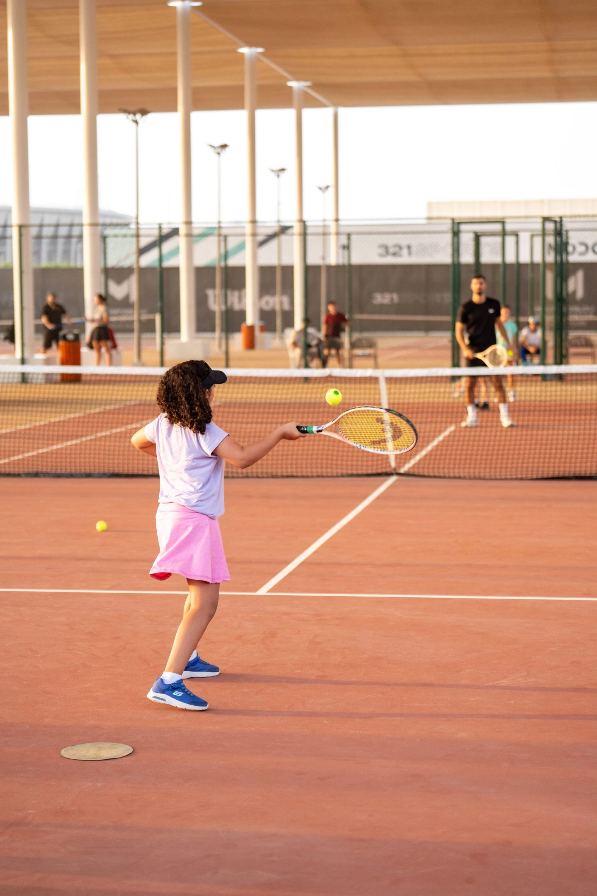 Young girl practicing a forehand during a tennis lesson on an outdoor court
