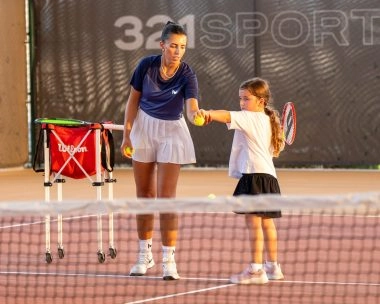 Mouratoglou coach teaching a young girl on the tennis courts of Hudayriyat Island in Abu Dhabi, focusing on technique and confidence.