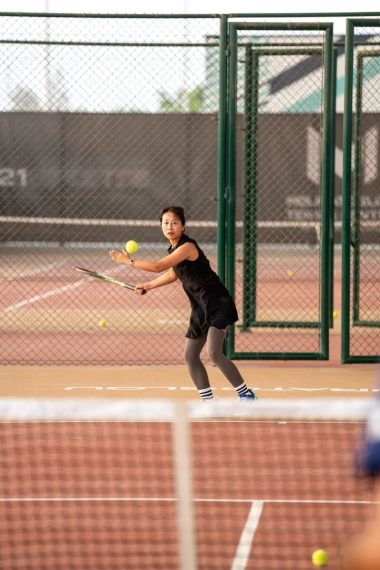 Adult player practicing on the tennis courts of Mouratoglou Tennis Center Hudayriyat Island in Abu Dhabi, surrounded by the sea breeze and palm trees.