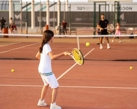Young girl practicing a forehand during a tennis lesson on an outdoor court
