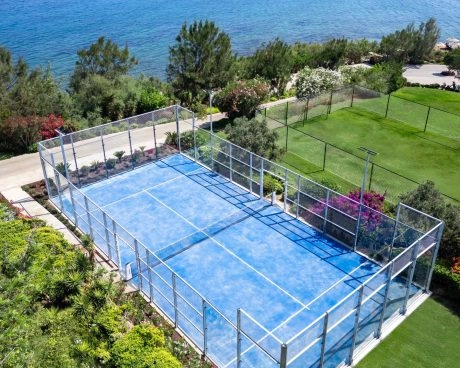 Blue padel court in Bodrum surrounded by greenery and sea views.