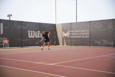 Tennis player getting ready to return a shot at Mouratoglou Tennis Center Hudayriyat Island in Abu Dhabi, showing focus and determination.