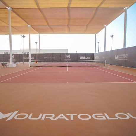 Covered clay tennis court with Mouratoglou branding and professional training setup